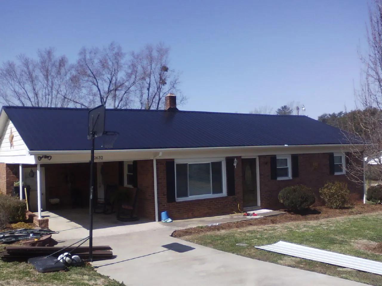 Finished dark blue metal roof on a brick ranch with a carport in Sherwood